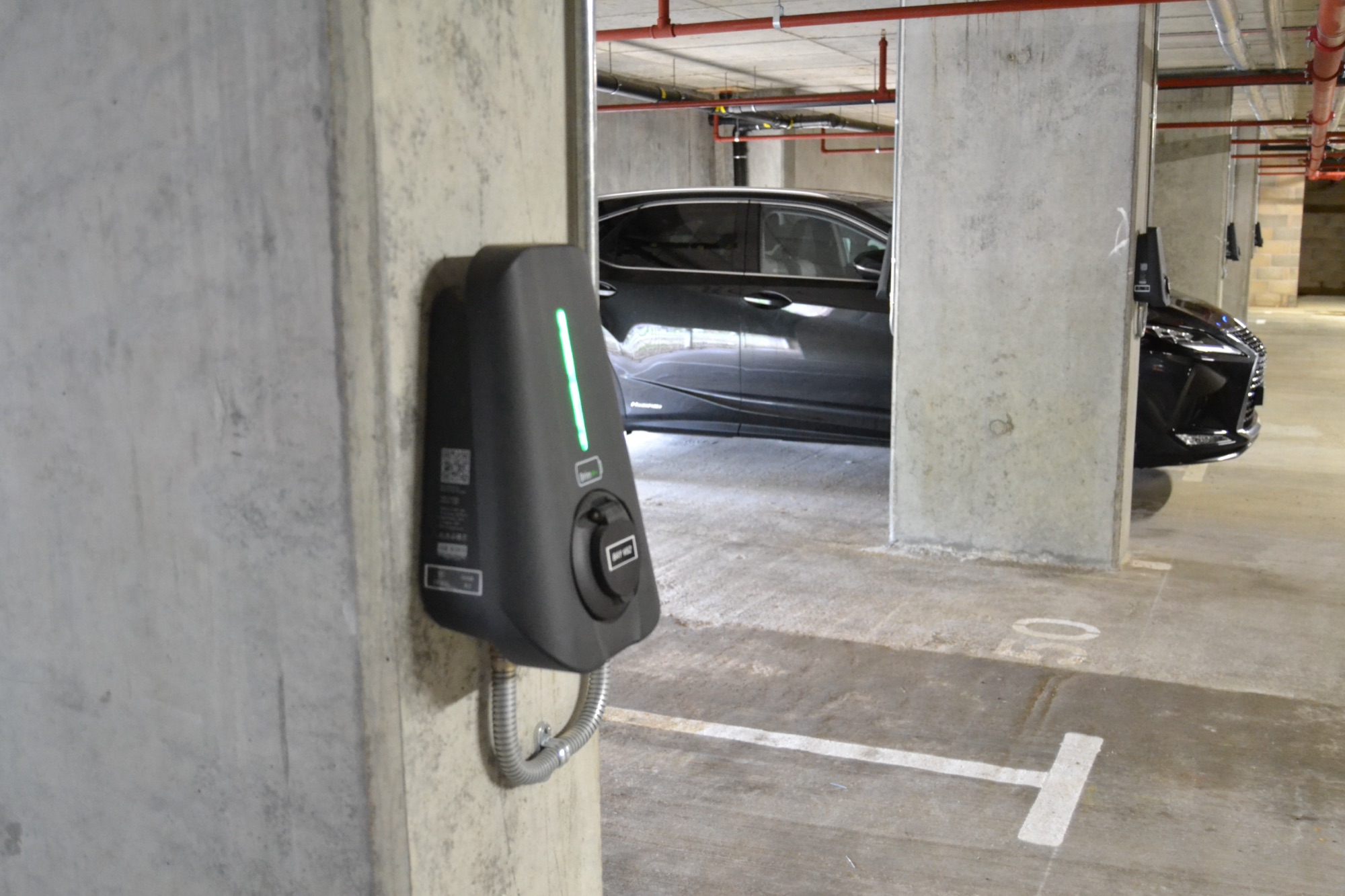 A Brim charger on a concrete column in an underground residents’ car park, with cars in the bays beyond it